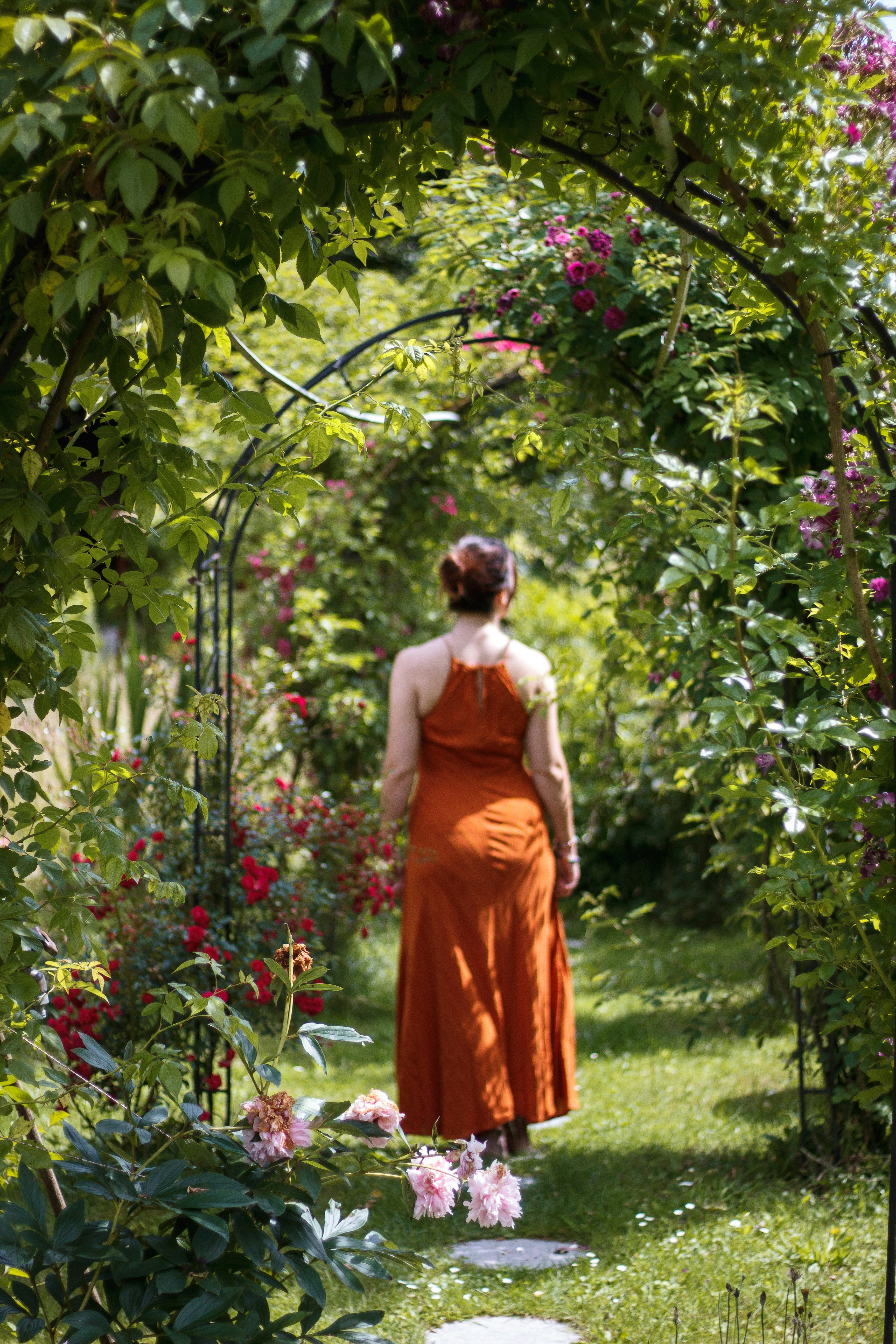 woman in orange dress standing on green grass field during daytime